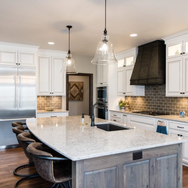 New Quay Cambria Quartz Kitchen Countertops with White and Gray Wood Cabinets, Wood Floors, and Bar Stools