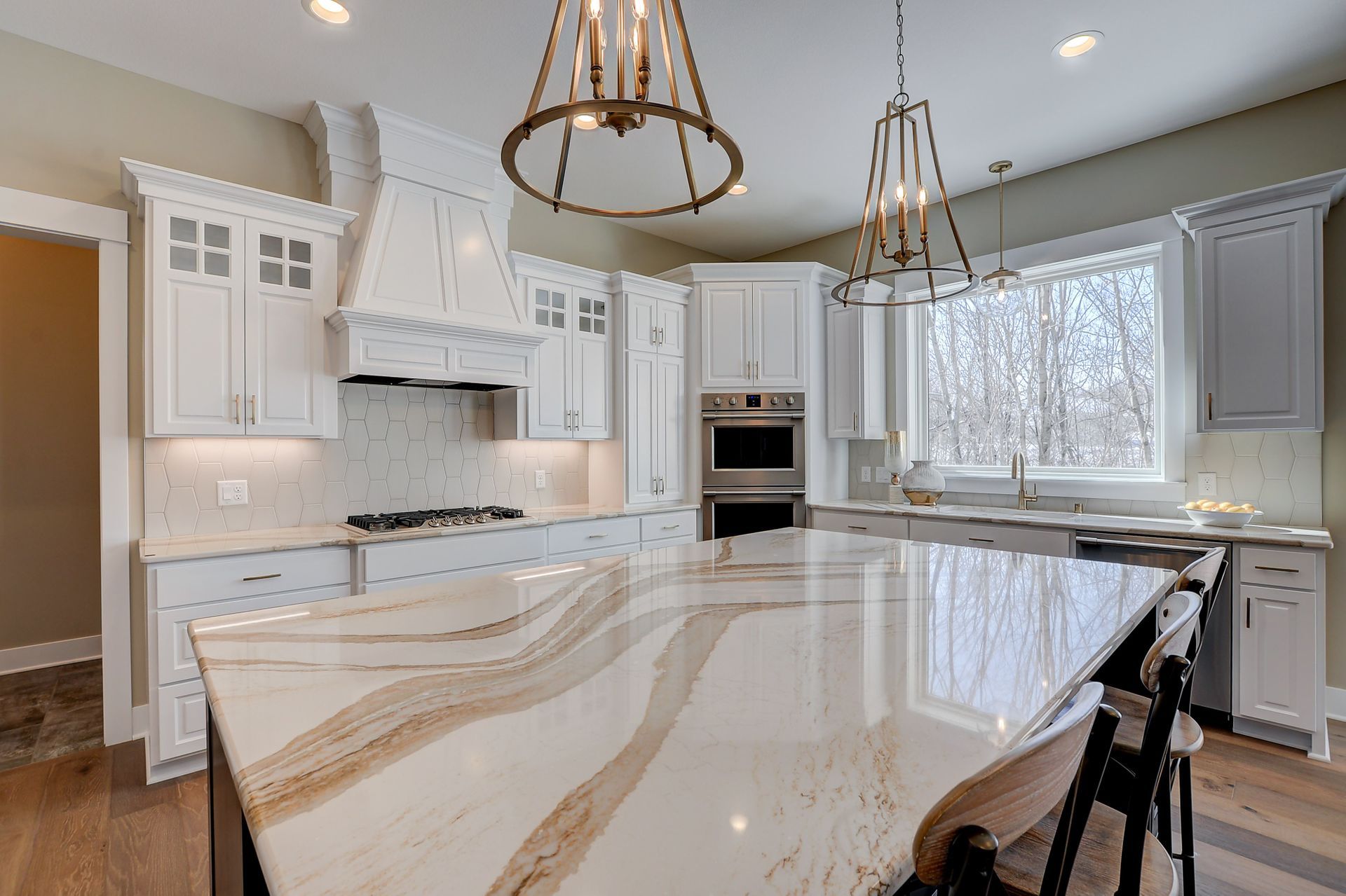Brittanicca Gold Cambria Quartz Kitchen Countertops with White Wood Cabinets, Wood Floors, and Bar Stools