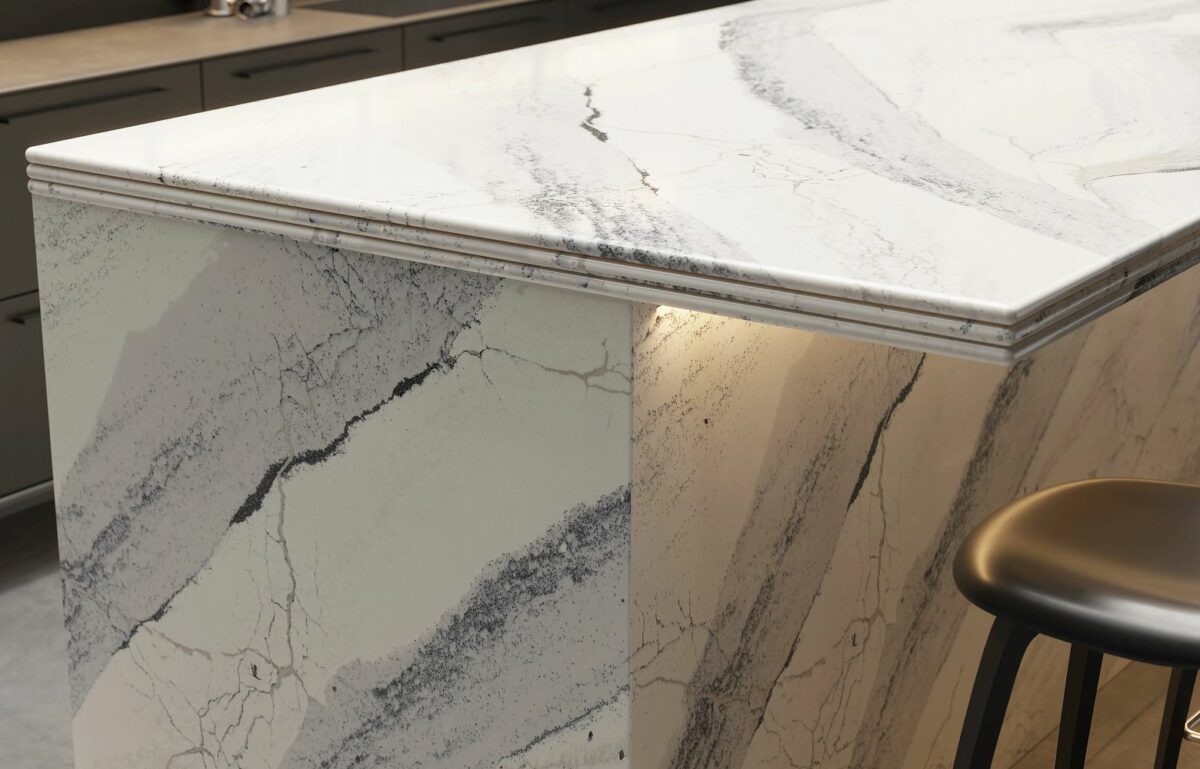 Close-up view of Cambria Windsor Steel Satin Ridge Quartz, showcasing its steel-toned wave patterns, warm honey-colored sand backdrop, and contrasting cool charcoal elements installed for kitchen countertops.